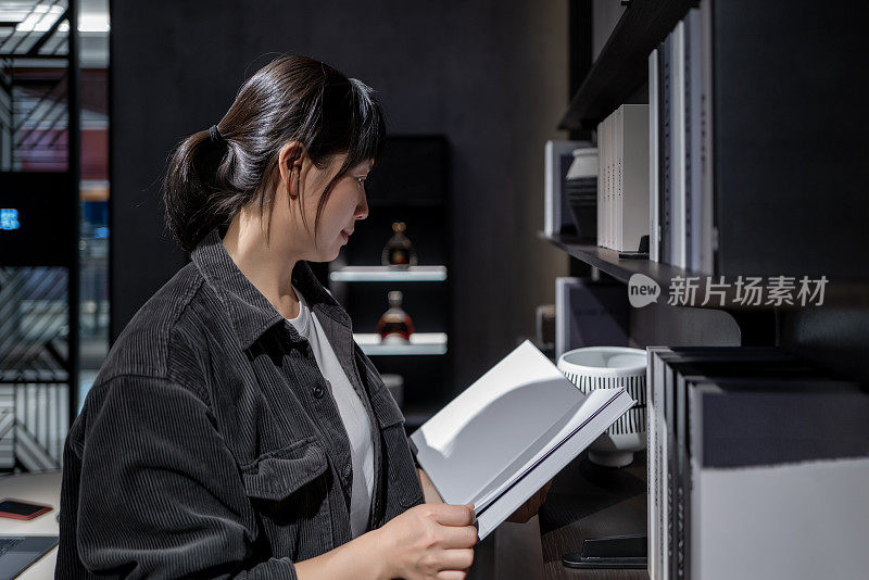 A woman selects books on the bookshelf for reading